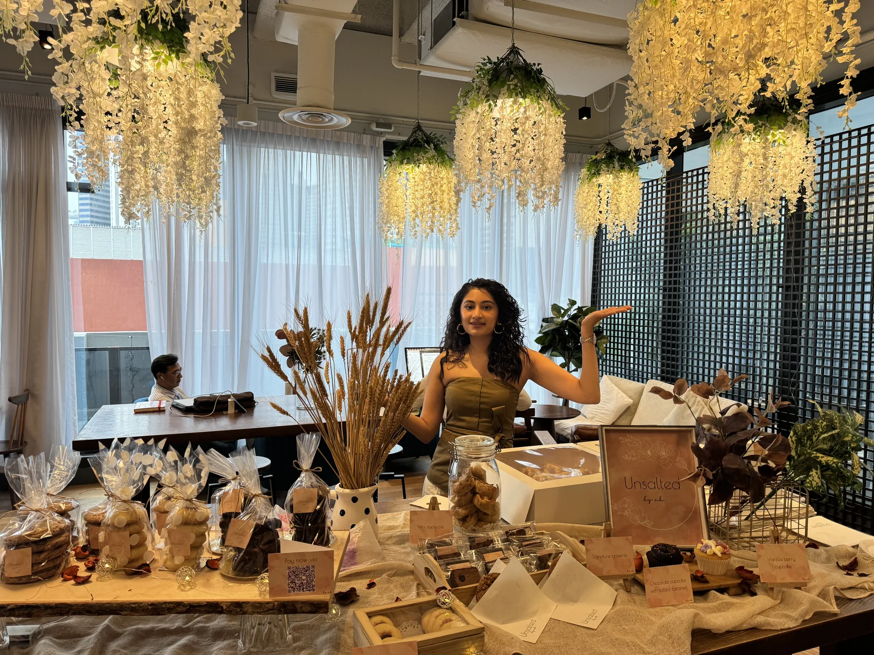Woman behind a dessert table under hanging white wisteria installations