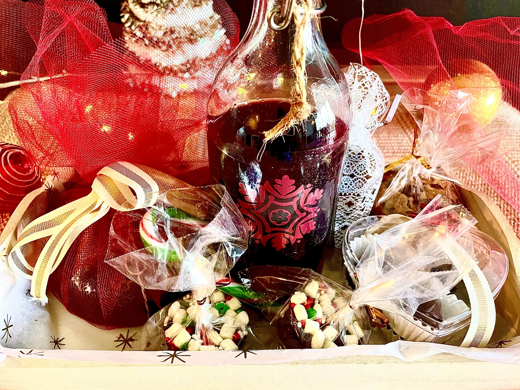 Abundant festive gift basket with sparkling wine, sweets, ribbons and fairy lights