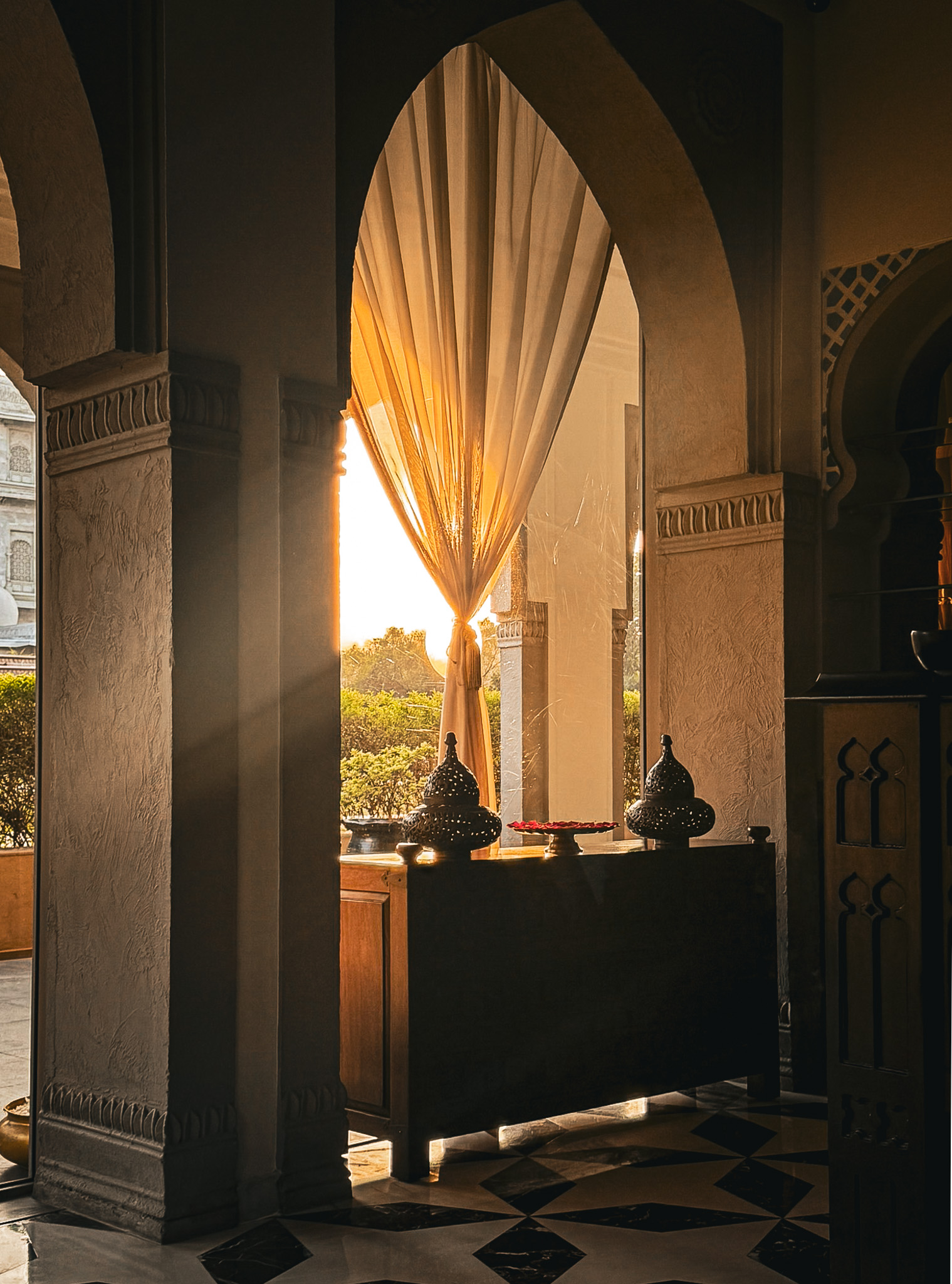 Golden sunlight streaming through a Mughal arched doorway with sheer curtains