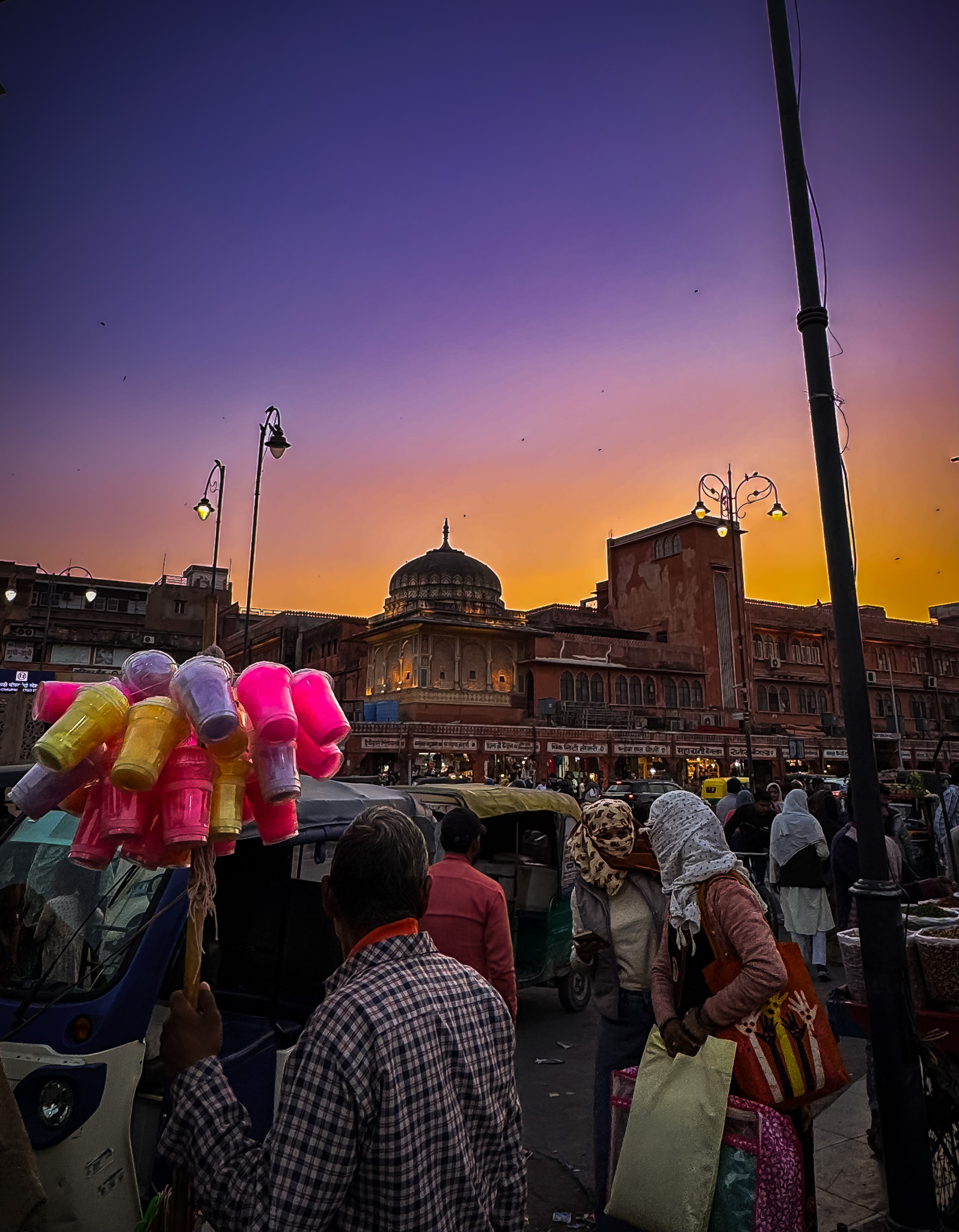 Jaipur market at dusk — a vendor holds plastic cups against a purple-gold sky