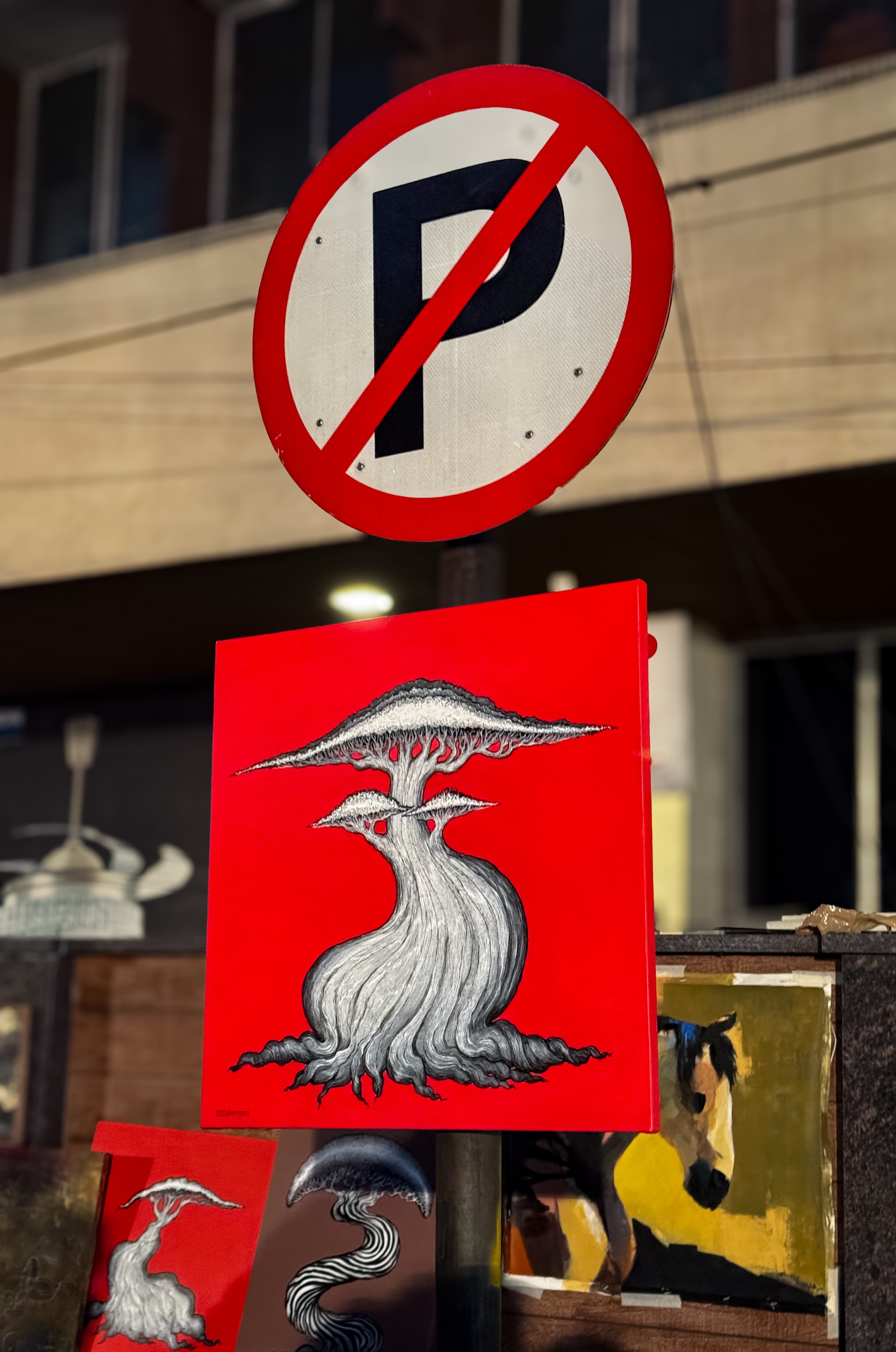 Vivid red street-art print of a surreal mushroom tree at a night art market