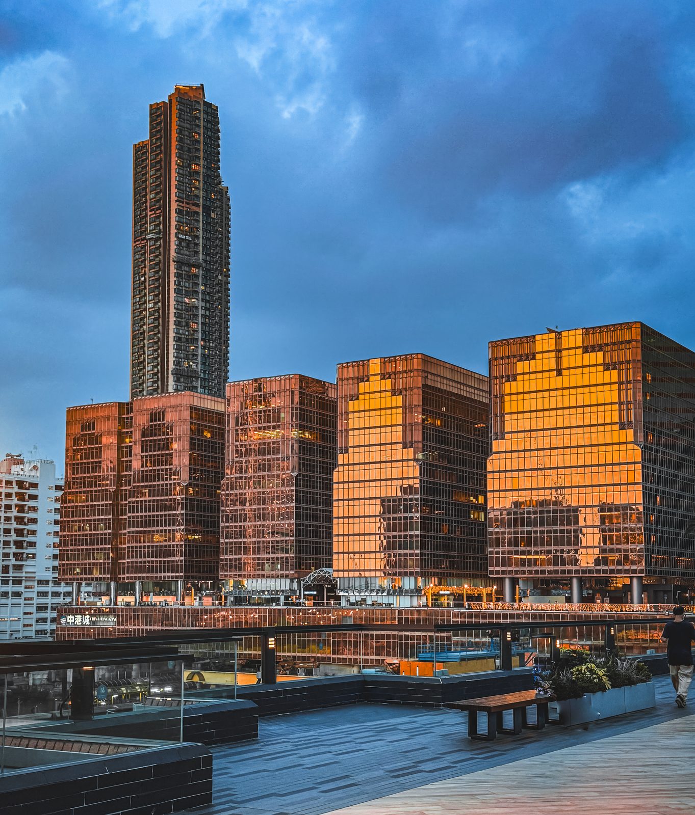 Golden high-rise towers catching late sun above a harbour promenade