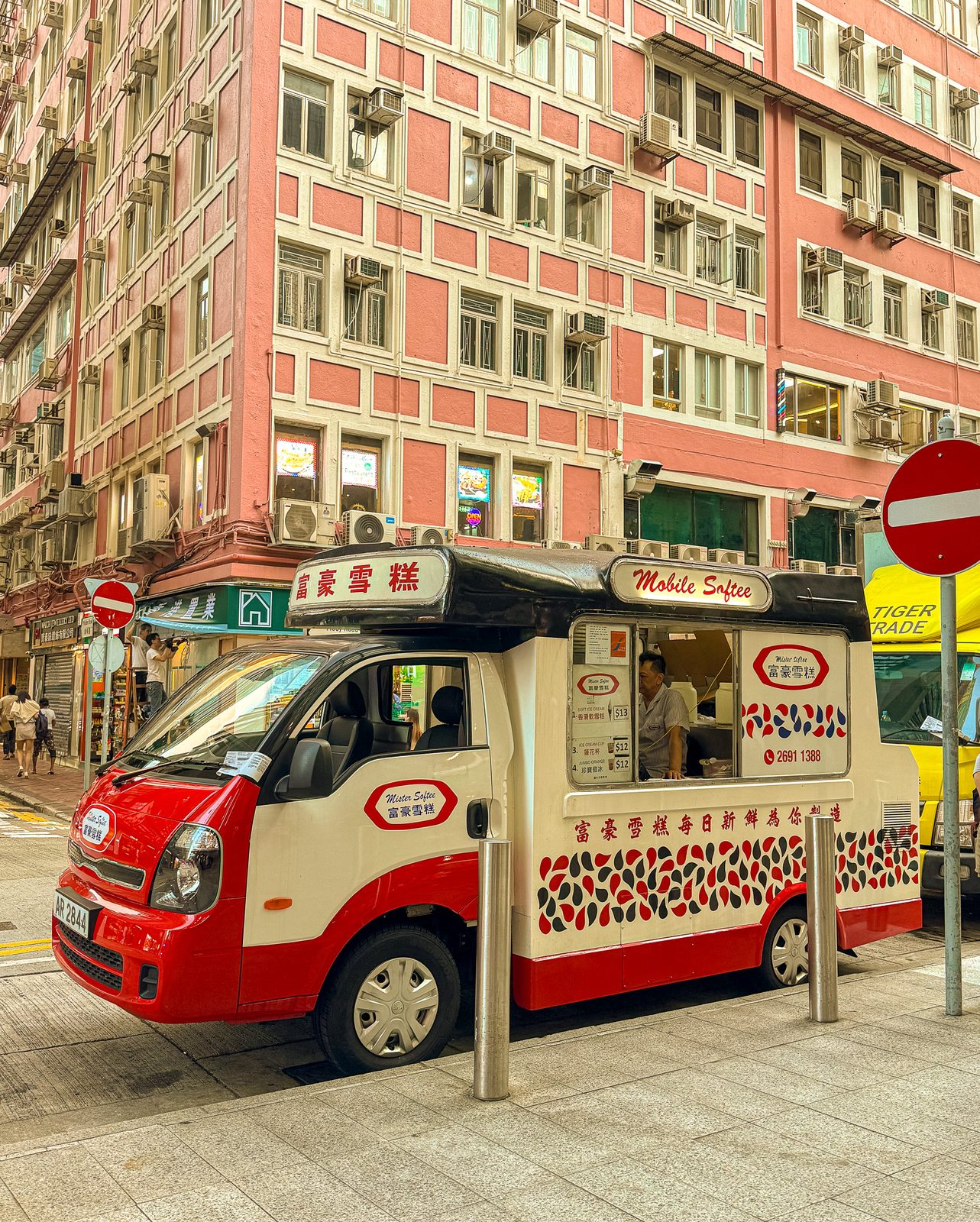 Red ice-cream truck parked against a pink colonial building