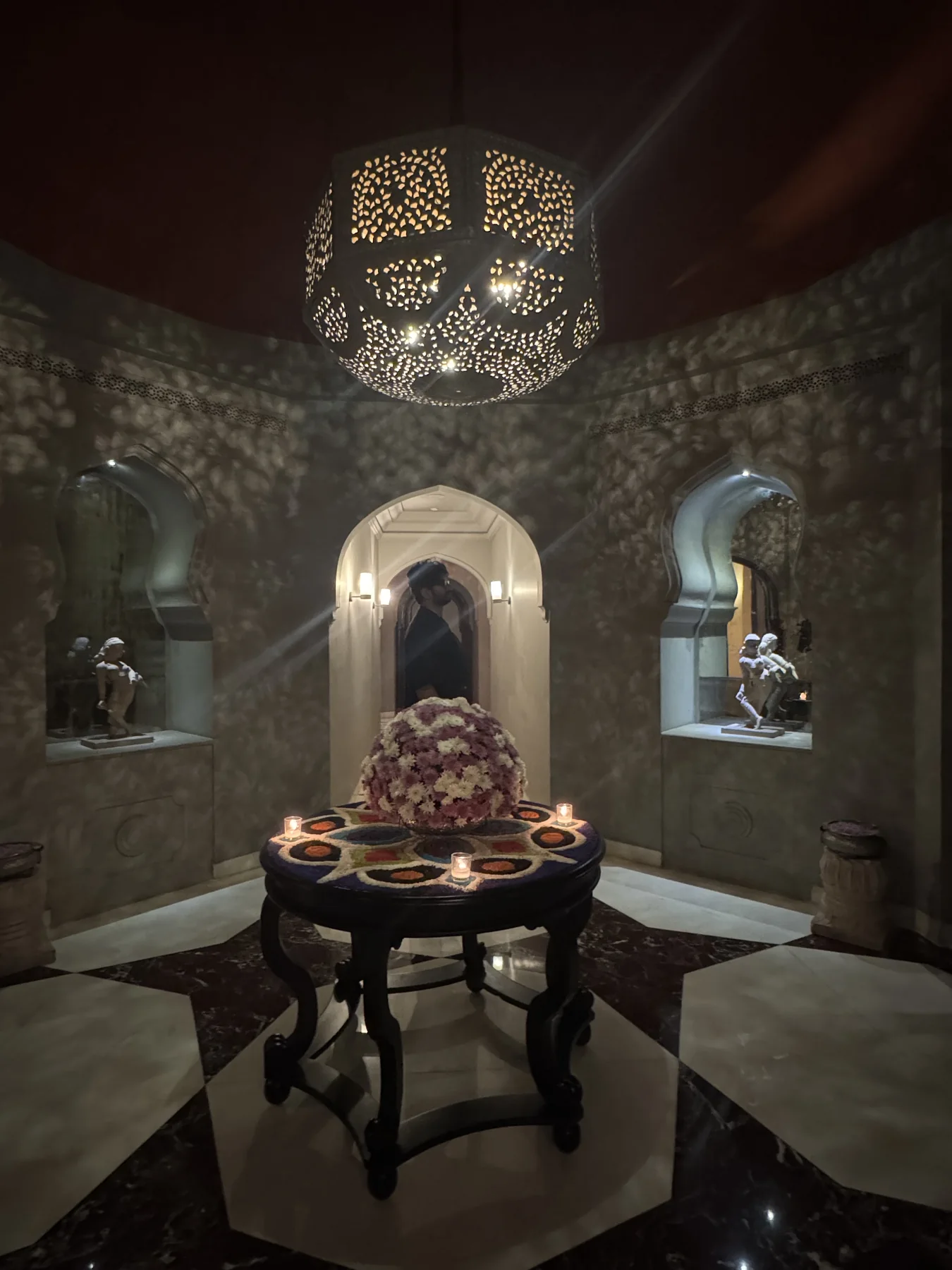 Ornate brass lantern casting lace-like patterns across a Mughal-arched room