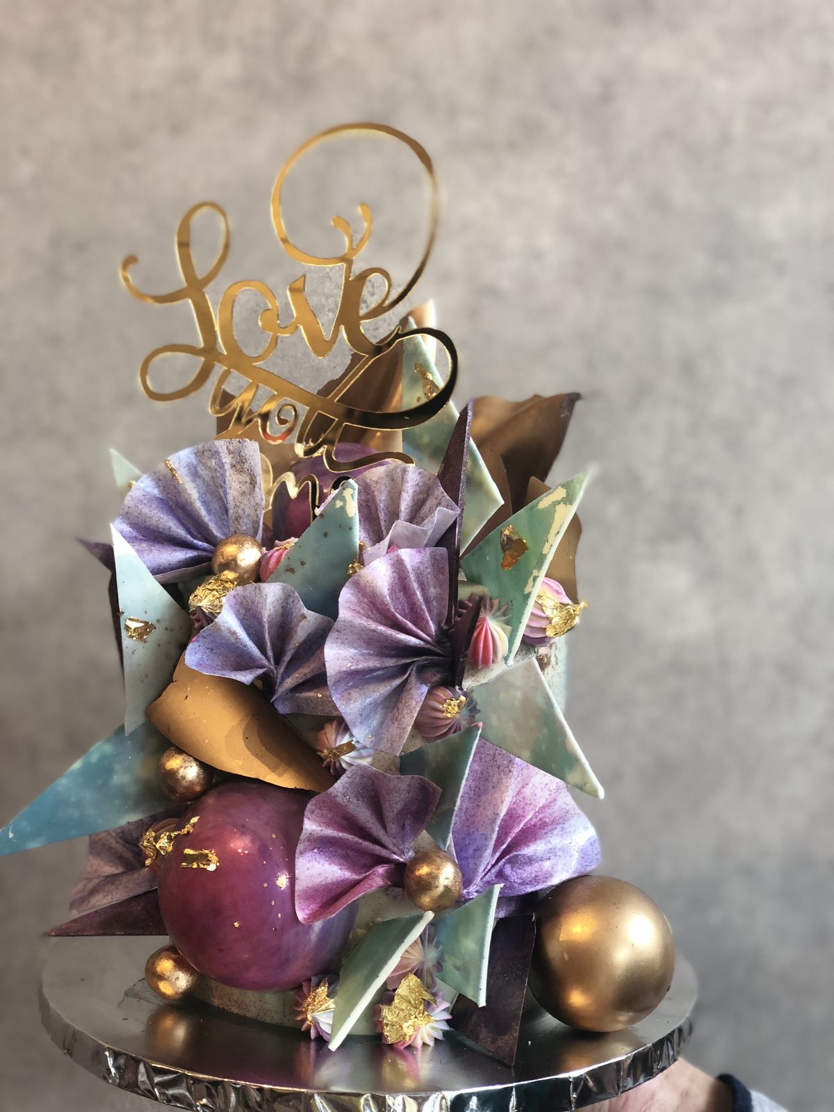 Deep purple cake with sugar sails, gilded shards and a gold Love topper