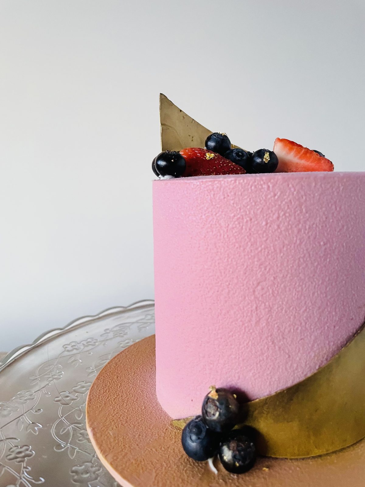 Blush pink entremet with dark berries and a chocolate sail
