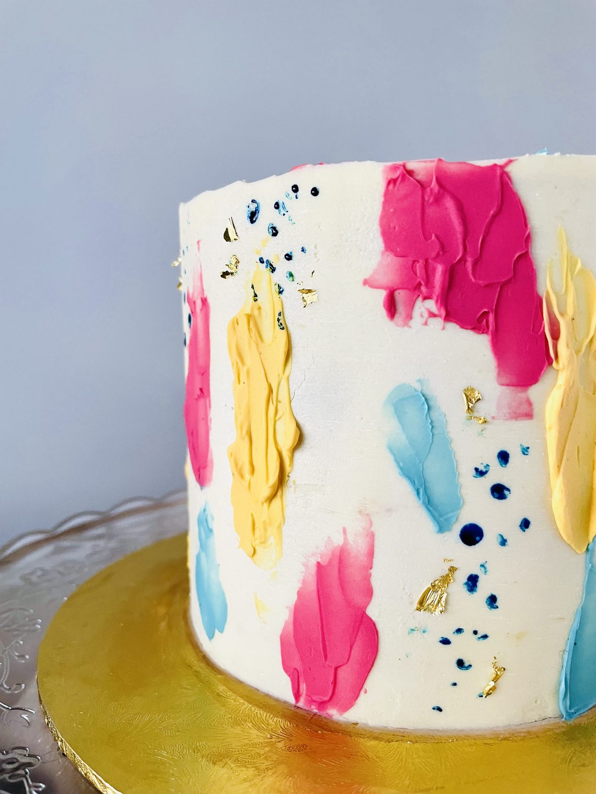White cake painted with pink, blue and gold brushstrokes