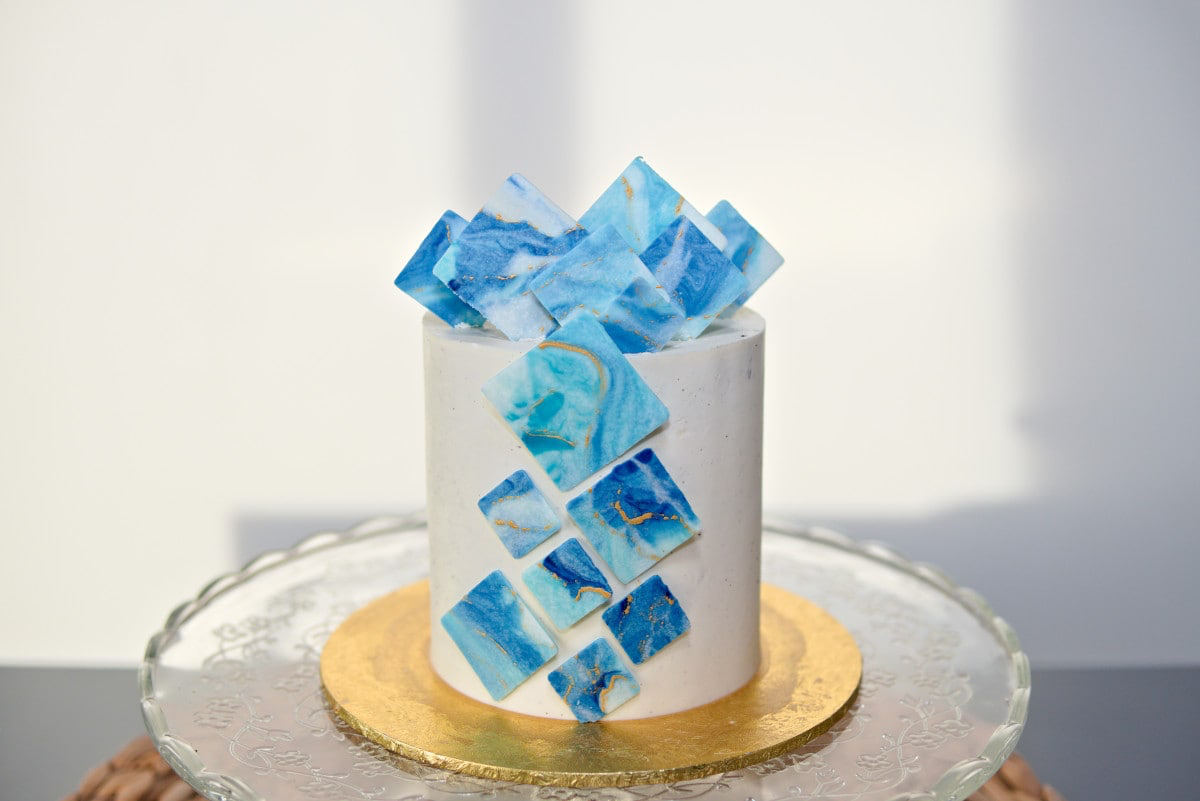 White cake with a diagonal cascade of blue sugar-glass shards