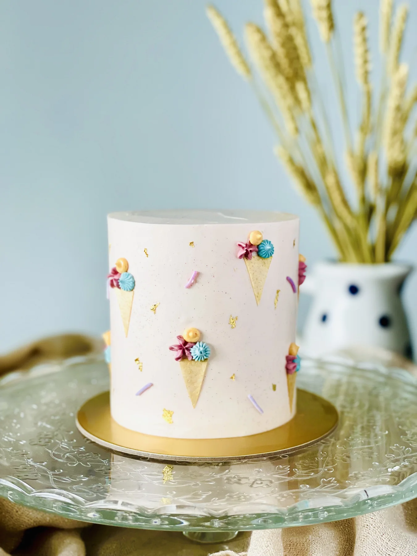 Pale blush cake with miniature ice cream cone motifs and gold leaf flecks