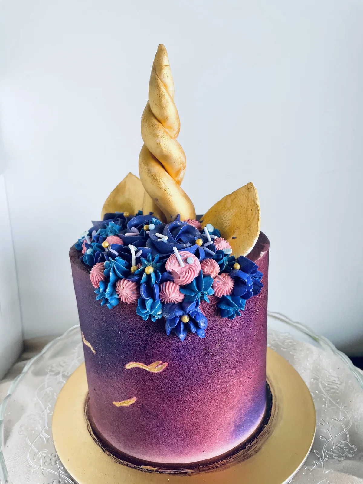 Galaxy-toned unicorn cake with a twisted gold horn and piped florals